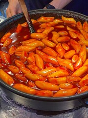 Spicy Korean tteokbokki with chewy rice cakes in a vibrant red sauce, topped with sesame seeds and green onions. A popular street food known for its addictive flavor and satisfying texture.