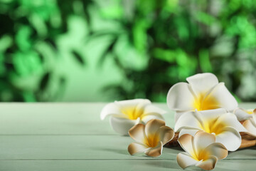 Beautiful plumeria flowers bamboo mat on wooden table outdoors