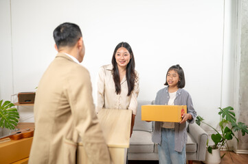 Home Moving Day: A family, full of excitement, joyfully works together, carrying cardboard boxes as they prepare to move into their new home, ready for the next chapter.