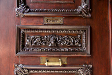 Close-up of an ornate antique wooden door with handcrafted metal mailbox and golden handle, illuminated by warm afternoon light in Puebla, Mexico. Elegant details, tradition, and architectural heritag