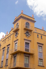 Vibrant yellow historic building in Puebla, Mexico, with intricate Talavera tile accents, showcasing colonial and European-Mexican architectural fusion.