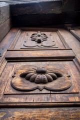 Close-up detail of an aged wooden door with hand-carved floral motifs, worn texture, and warm golden tones created by natural afternoon light.