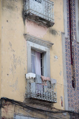 Silent balcony scene in Puebla, Mexico, where sun-bleached walls, drying clothes and soft textiles reveal private life unfolding behind historic urban facades.