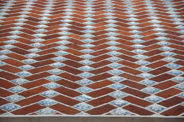 Texture of Mexican colonial wall with red bricks and scattered talavera tiles, showcasing craftsmanship and historic charm.