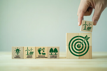 Hand stacking wooden blocks with sustainability symbols toward a green target goal concept