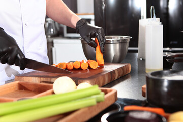 Cook cuts carrots in kitchen. Cooking vegan dish. Cut carrots into strips. Healthy food. Concept of cooking.