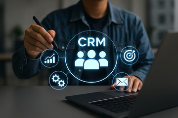customer relationship management (crm) system concept with icons for data analysis, process, target, and communication on a futuristic screen while a man works on a laptop