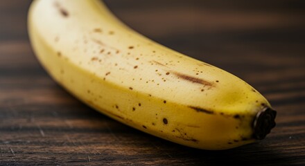 Ripe Yellow Banana with Brown Spots on Wooden Surface