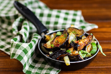 Fried eggplants with onions and fresh herbs in a rustic style