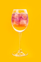 Alcoholic cocktail in a tall glass on a yellow background.