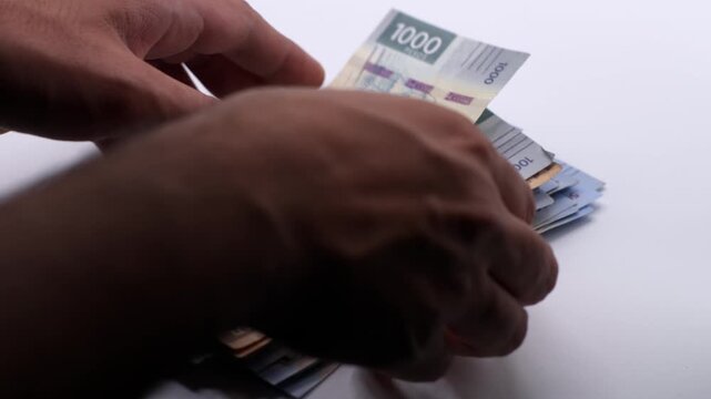 Hand sorting several Mexican peso bills. Slow motion close up