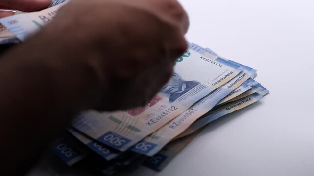 Person counting 500 Mexican pesos bills one by one. Slow motion