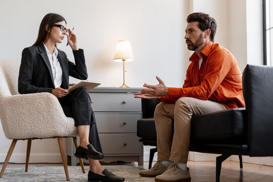Female, confident psychologist providing counseling support to male patient during therapy session