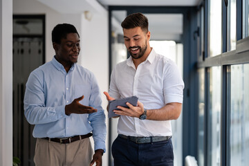 Two confident businessmen discussing ideas with digital tablet