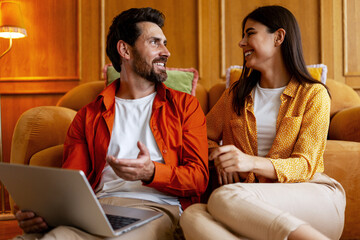 Smiling couple using laptop having communication at home sitting on floor