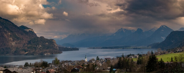 Dramatic evening light over Fuschlsee lake in Salzburg, Austria – alpine landscape with village, mountains and moody clouds before sunset