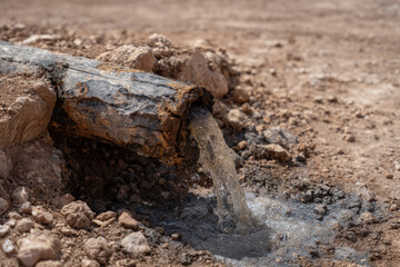 Rusty pipe leaking water polluted sludge desert ground erosion