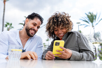 Happy couple enjoying outdoor cafe browsing smartphone