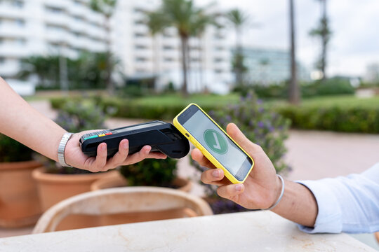 Hands making contactless mobile payment using smartphone and terminal