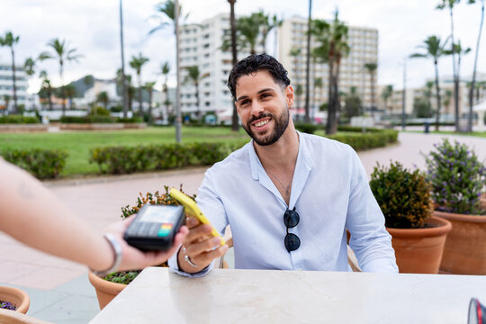 Man paying contactless with smartphone at outdoor cafe