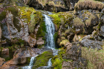Obraz premium Close-up of small waterfall flowing over moss-covered rocks in alpine forest near Hallstatt, Austria