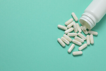 Vitamin pills and bottle on green background, top view. Space for text
