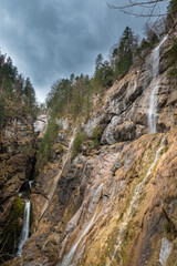 Powerful alpine waterfalls flowing down steep cliffs under dramatic sky - Waldbachstrub waterfall near Hallstatt, Austria