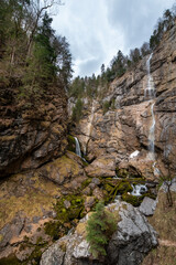 Powerful alpine waterfalls flowing down steep cliffs under dramatic sky - Waldbachstrub waterfall near Hallstatt, Austria
