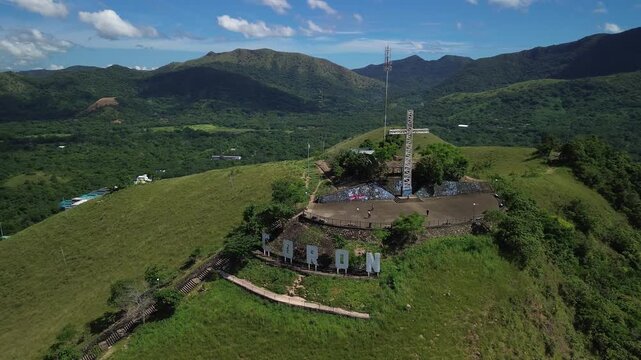 Oblique aerial view of Mount Tapyas summit above Coron with the hilltop cross Coron letters green ridges fenced overlook and surrounding mountain valley