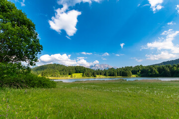 Geroldsee (Wagenbrüchsee) in Bavaria, Germany, with alpine meadow, forest and mountains under blue sky