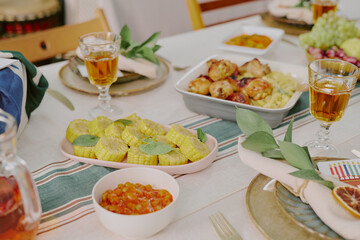 Closeup showing festive Kwanzaa table setting with corn, roasted vegetables, fruit, and glasses of drink arranged on table, emphasizing traditional holiday celebration meal