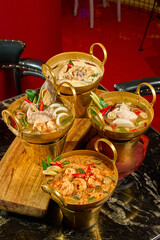 Authentic Thai Spicy and Sour Fish Soup (Tom Yum Pla) in a Traditional Brass Hot Pot, Isolated