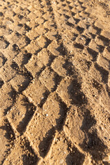 tracks in the sand on a part of the road in a field, sand on the road in a field with traces of heavy agricultural or construction vehicles