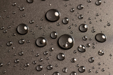 the glossy black surface is covered with drops of clean water, a large number of drops of water