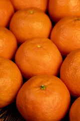 Unpeeled orange tangerines stacked together, a large number of ripe tangerines on the table