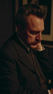 Vintage-style video scene of a man writing at a wooden desk in a dimly lit library, captured from a low angle to emphasize the room's grandeur.