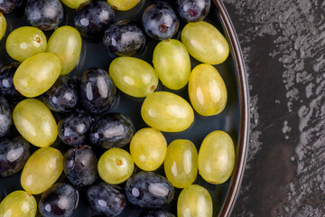 beautiful ripe grapes of blue and green color close up, covered with drops of water, wet fruits of pure green and blue grapes during cooking