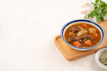 Tomato flavor beef stew with radish and carrot in bowl.