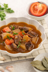 Tomato flavor beef stew with radish and carrot in bowl.