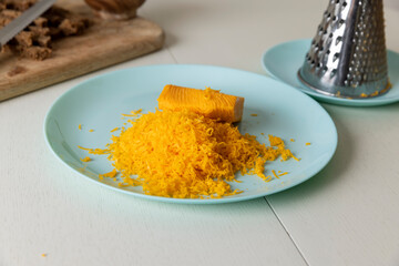 a piece of whole cheese and a large amount of finely grated yellow cheese made from milk, grating fresh orange cheese for pizza or pasta