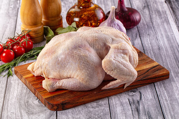 Raw whole chicken over board