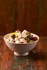 Green and kalamata olives and feta cheese on rustic wooden background. Soft focus.	
