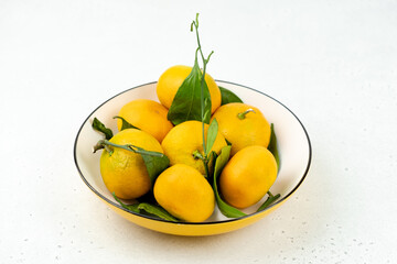 Tangerines in a bowl, light background, close-up, winter fruits.