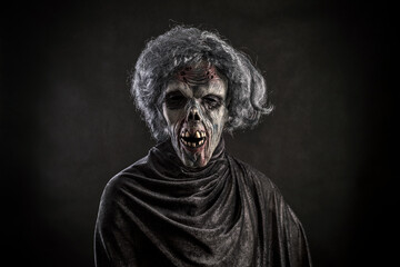 Scary zombie with gray hair over dark background