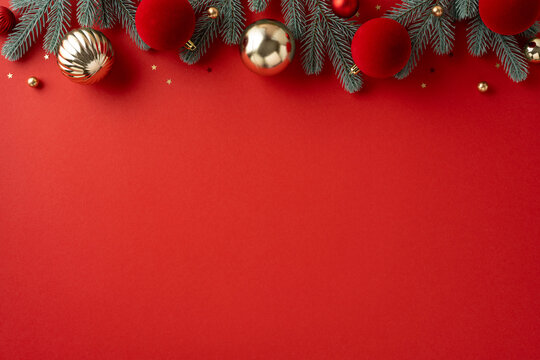 Vivid red background framed with pine garland and gold and red Christmas ornaments creates a warm holiday mood suitable for Christmas and New Year greetings and seasonal themes