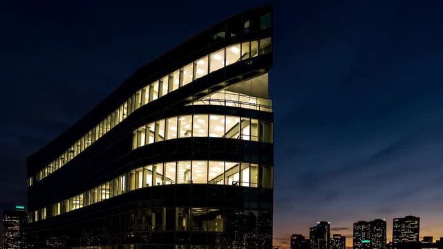 Timelapse of sunset over office building with automatic smart lighting turning on.