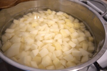 Cubes of raw potato in water inside a cooking pan. Close-up image of homemade preparation for cooking.