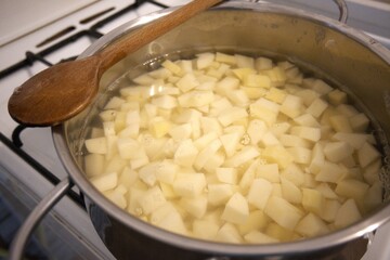 Cubes of raw potato in water inside a cooking pan. Close-up image of homemade preparation for cooking.