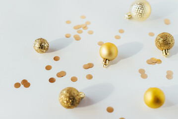 Golden Christmas balls and confetti on a white table in bright light
