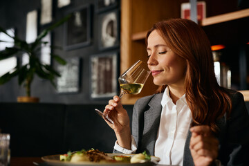 Smiling businessman having glass of wine during lunch in restaurant.